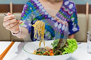 Hand holding fork eating spaghetti in restaurant.