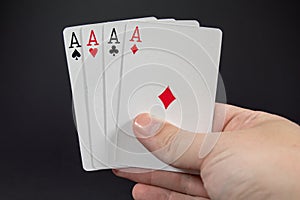 A hand holding the four Aces from playing cards