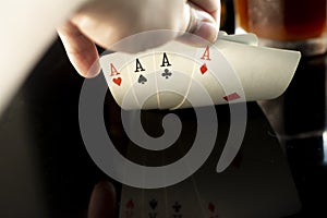 Hand holding four playing cards with aces