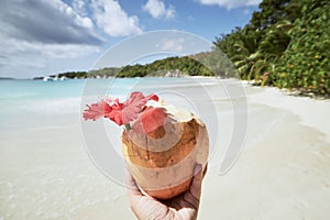 Hand holding fresh coconut drink on beach