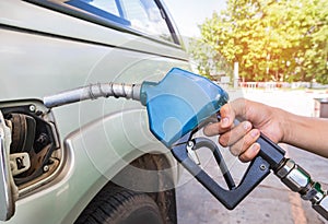 Hand holding fuel nozzle refueling gas pump for the car