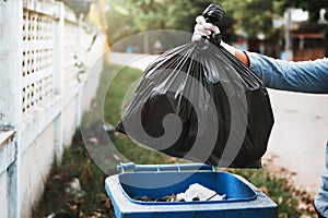 hand holding garbage black bag putting in to trash