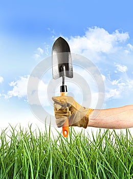 Hand holding garden trowel against blue sky photo