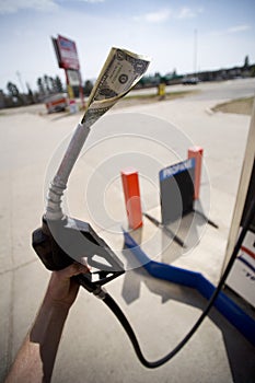 Hand holding gas pump with money in nozzle