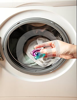 Hand holding gel caps for washing machine. Household laundry equipment. Spring clothes cleaning