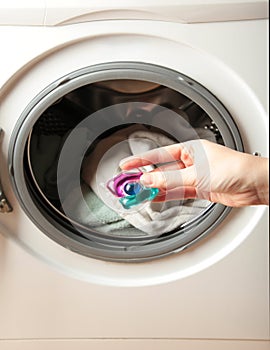 Hand holding gel caps for washing machine. Household laundry equipment. Spring clothes cleaning photo