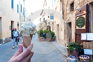 Hand holding gelato, ice-cream with blur background of a old town in Italy