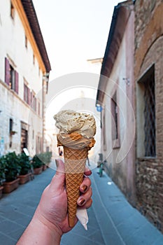 Hand holding gelato, ice-cream with blur background of a old town in Italy