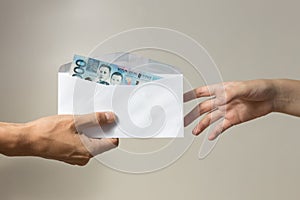 Hand holding giving cash banknote of one thousand Philippinesin envelope peso paying bills, payment procedure or bribe, salary
