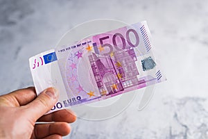 Hand holding and giving five hundred euro banknotes. Money in man hands on gray background