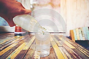 Hand holding the glass bottle of water cool and pouring water in