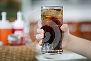 Hand holding glass of cola drink