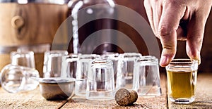 Hand holding glass of drips, sugar cane distilled beverage, in rustic wooden setting