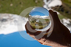 Hand holding glass sphere alps in summer