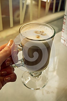 Hand holding Glass of Tasty classic coffee latte macchiato with