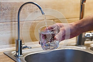 Hand holding a glass of water. a man  pouring water from filter tap. clean water and healthy life concept