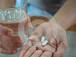 Hand holding glass of water and pills, tacking medicine concept