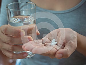 Hand holding glass of water and pills, tacking medicine concept photo