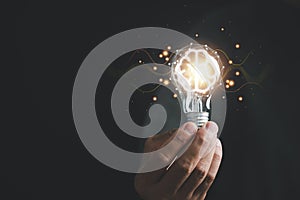 A hand holding a glowing light bulb, signifying the connection between creative ideas