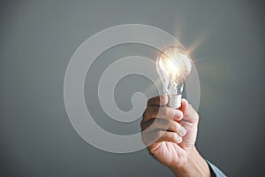 A hand holding a glowing light bulb, signifying the connection between creative ideas photo