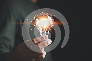 A hand holding a glowing light bulb, signifying the connection between creative ideas photo