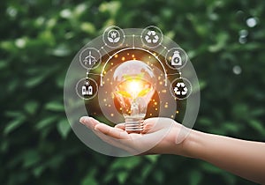 Hand holding a glowing light bulb with sustainable technology icons in a circle
