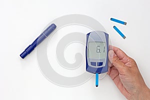 Hand holding glucometer with 6.1 result on display