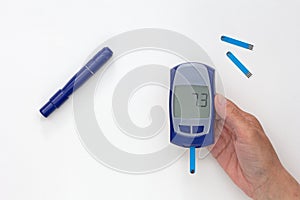 Hand holding glucometer with 7.3 result on display