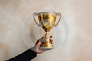 Hand holding a gold trophy. Sports, champion with trophy