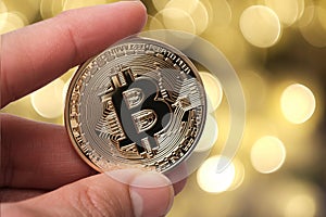 Hand holding golden bitcoin on abstract background