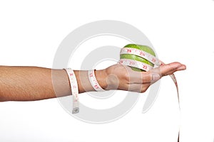 Hand holding green apple with measuring tape.