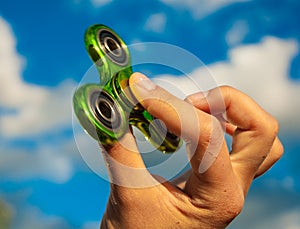 Hand holding green fidget spinner toy