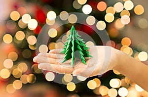 hand holding green paper origami christmas tree