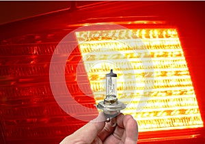 Hand holding halogen light bulb vehicle spare parts on car back lamp shiny in dark background