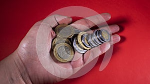 Hand holding a handful of Mexican pesos on a red background photo