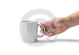 A hand holding the handle of a plain white ceramic mug against a