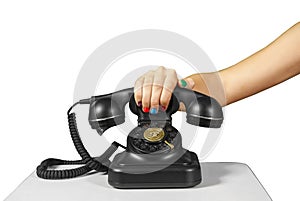 Hand holding the handset of an old black vintage rotary-style telephone