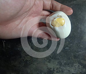 the hand holding a hard-boiled egg that has been removed from the shell