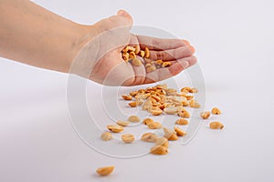 Hand holding heap of salt roasted peanuts on white background