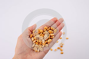 Hand holding heap of salt roasted peanuts on white background