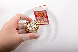 Hand holding Heart shape and Islamic Holy Quran