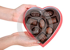 Hand holding heart shaped box with chocolates, isolated