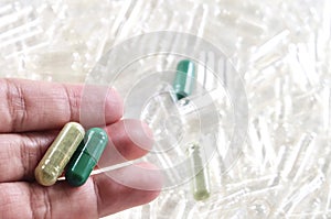 Hand Holding Herbal Medicine in Green Capsules