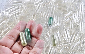 Hand Holding Herbal Medicine in Green Capsules