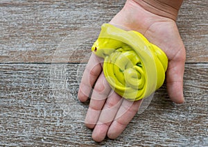 Hand holding homemade yellow slime with tinsel.