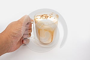 Hand holding hot  coffee with milky foam sprinkle with cocoa power for decoration in double wall glass isolated on white