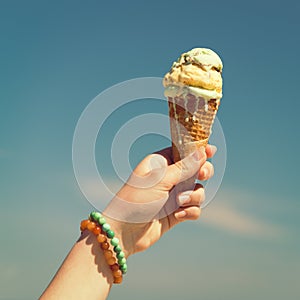 Hand holding ice cream cone on the sky background