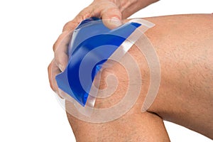 Hand holding ice gel pack on knee