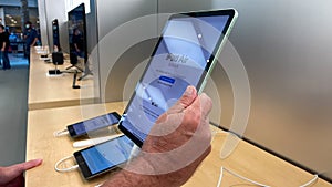 A hand holding a 10.9 inch iPad Air tablet computer at an Apple store