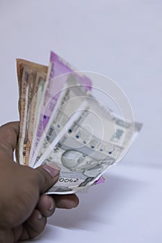 Hand holding Indian rupee notes against white